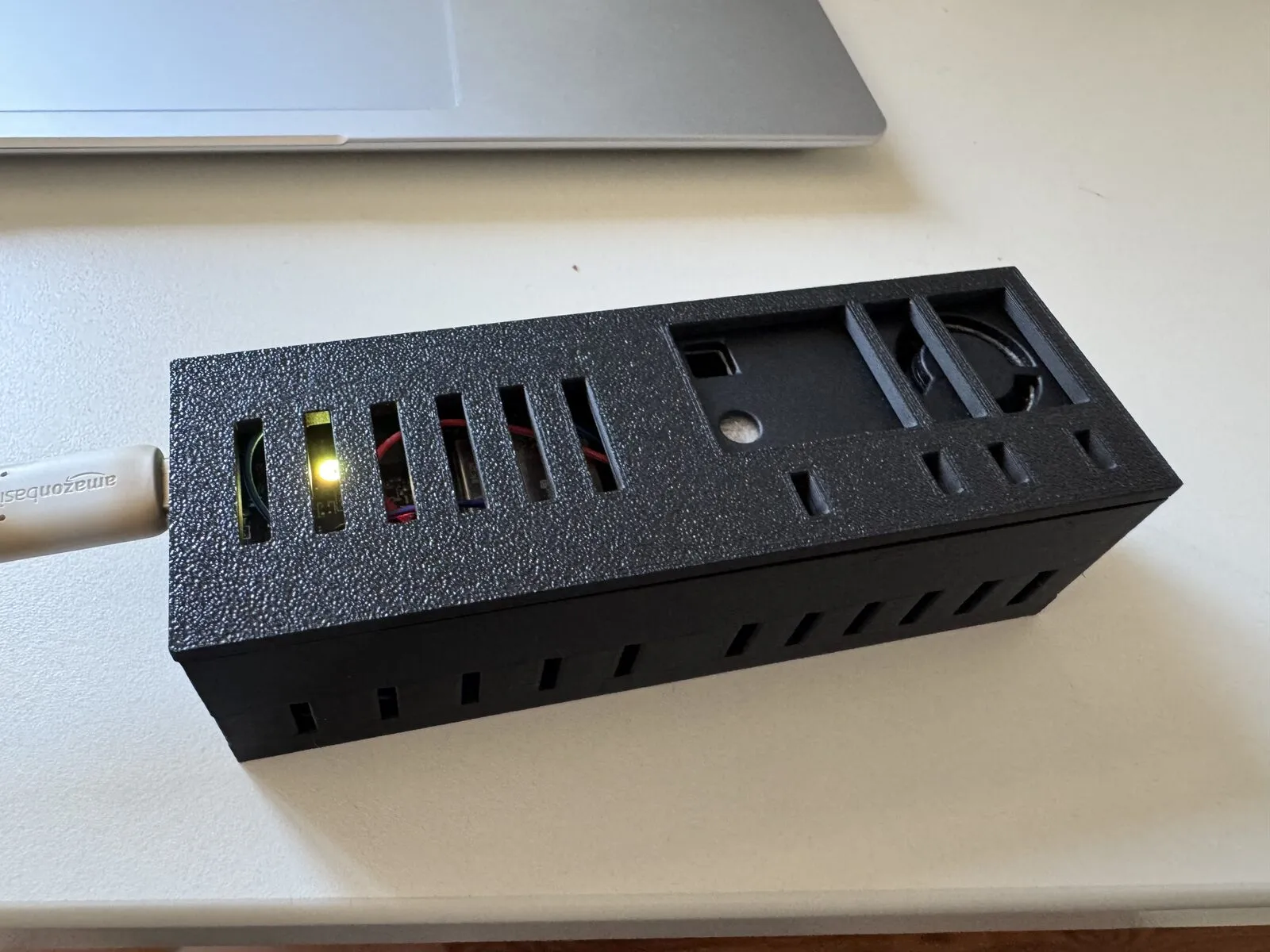 The closed enclosure with the status LED glowing green through the ventilation grille
