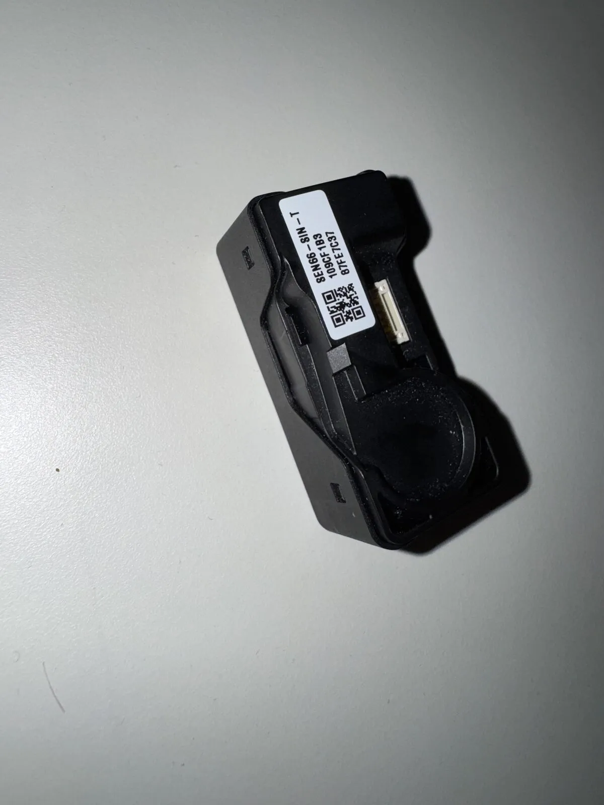 The bare SEN66 sensor module — a matchbox-sized housing with a fan opening, an air inlet, and a tiny connector on the side